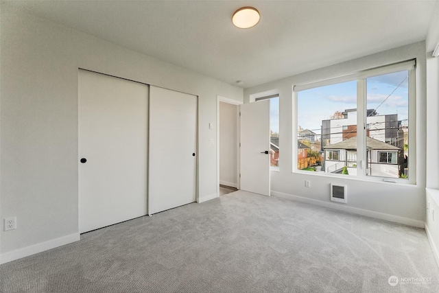 unfurnished bedroom with light carpet and a closet