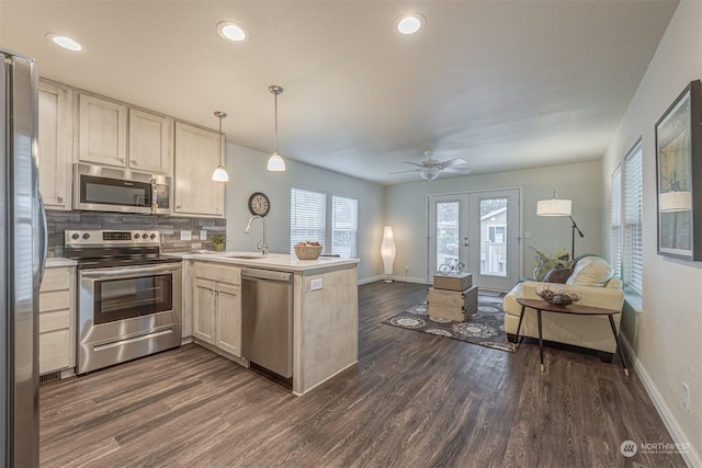 kitchen featuring sink, appliances with stainless steel finishes, dark hardwood / wood-style flooring, decorative light fixtures, and kitchen peninsula