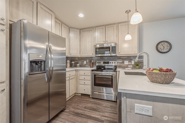 kitchen with dark hardwood / wood-style floors, pendant lighting, sink, decorative backsplash, and stainless steel appliances