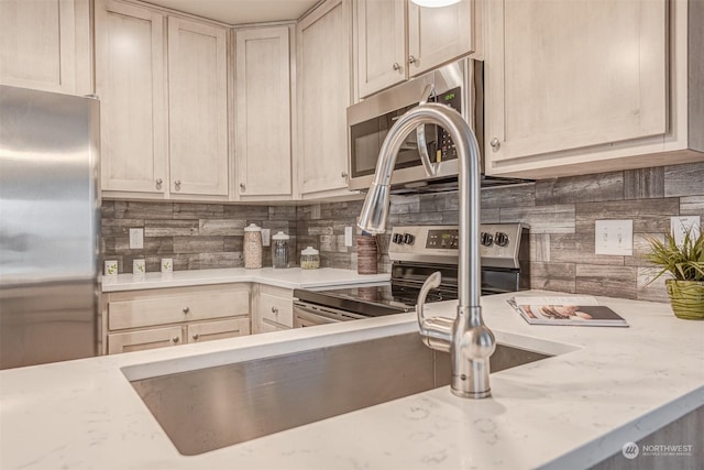 kitchen featuring stainless steel appliances, tasteful backsplash, and light brown cabinetry