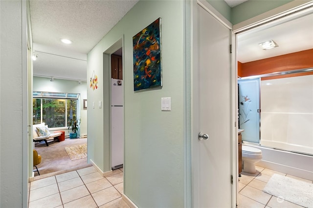 corridor featuring a textured ceiling and light tile patterned flooring