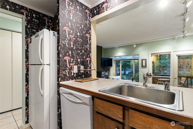 kitchen with white appliances, a textured ceiling, rail lighting, sink, and light tile patterned floors