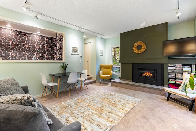 carpeted living room featuring rail lighting, a textured ceiling, and a tile fireplace