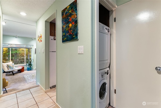 clothes washing area featuring a textured ceiling, light carpet, and stacked washer and dryer