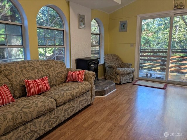 living room with a wood stove, light hardwood / wood-style flooring, and vaulted ceiling