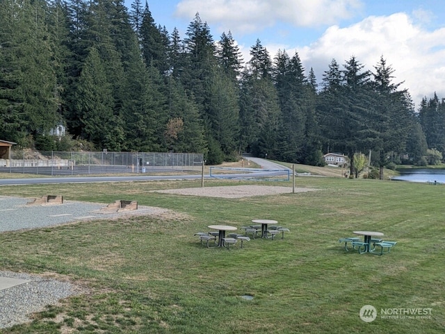 view of community featuring volleyball court, a lawn, and a water view