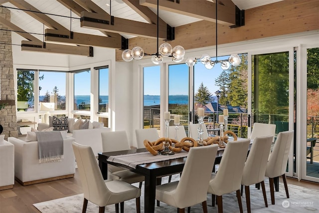 dining room featuring beamed ceiling, a water view, an inviting chandelier, and light hardwood / wood-style floors