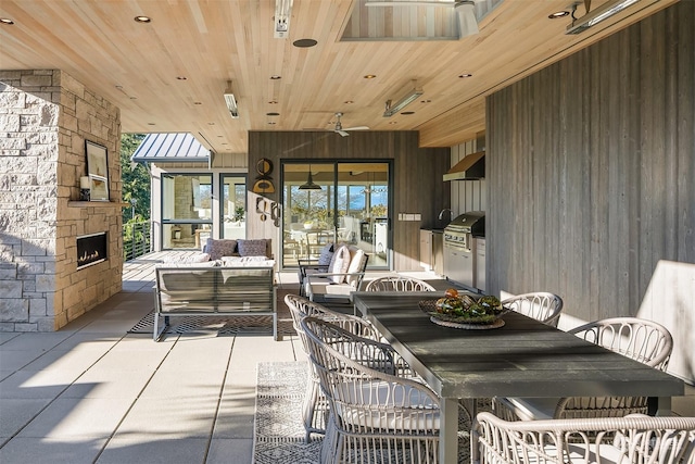 dining area featuring wood ceiling, an outdoor stone fireplace, and wood walls