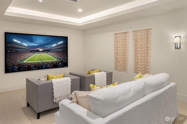 home theater room featuring light carpet and a tray ceiling