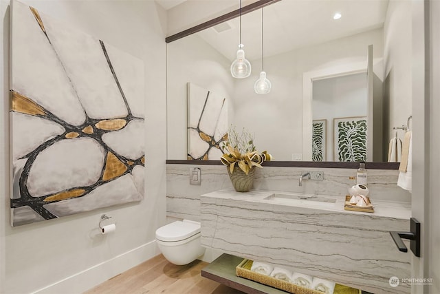 bathroom featuring wood-type flooring, toilet, vaulted ceiling, and vanity