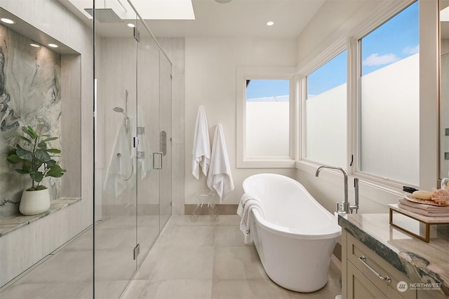 bathroom with vanity, shower with separate bathtub, and a skylight