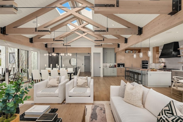 living room with beamed ceiling, a chandelier, high vaulted ceiling, and light wood-type flooring