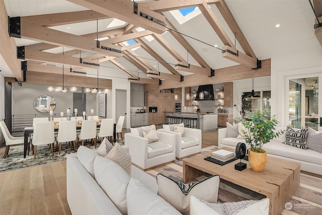 living room with light hardwood / wood-style flooring, beam ceiling, a skylight, high vaulted ceiling, and a chandelier