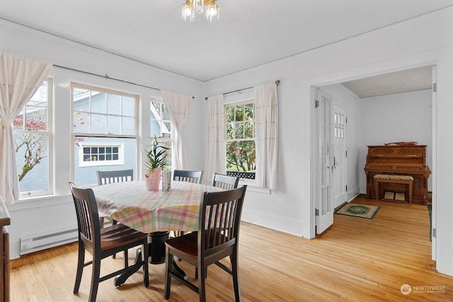 dining room with a baseboard heating unit and light hardwood / wood-style flooring