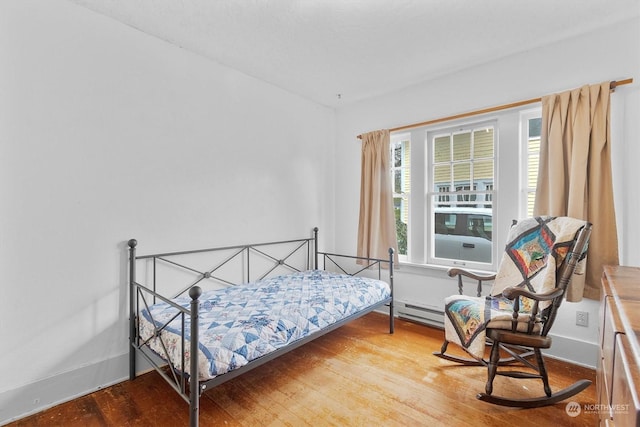 bedroom with a baseboard radiator, multiple windows, and hardwood / wood-style floors