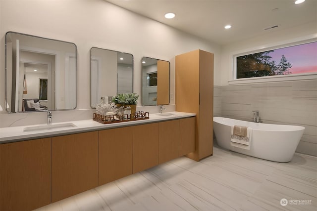 bathroom with a tub, tile walls, and vanity