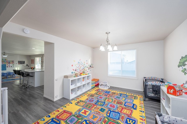 rec room featuring ceiling fan with notable chandelier and dark hardwood / wood-style flooring