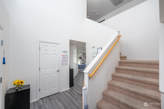 stairway featuring a high ceiling and wood-type flooring