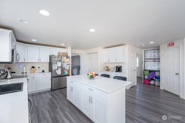 kitchen with sink, white cabinetry, a center island, dark hardwood / wood-style flooring, and stainless steel appliances