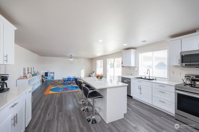 kitchen featuring sink, a breakfast bar area, a kitchen island, stainless steel appliances, and white cabinets