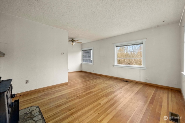 unfurnished living room featuring ceiling fan, a textured ceiling, and light hardwood / wood-style flooring