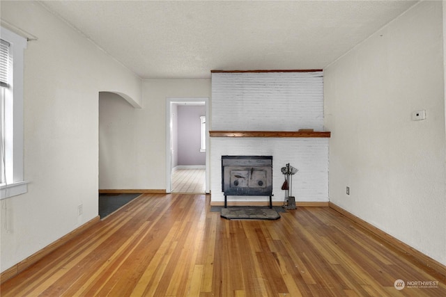 unfurnished living room with a textured ceiling, a fireplace, and hardwood / wood-style floors