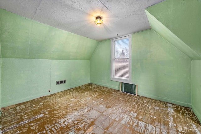 additional living space with a textured ceiling and lofted ceiling