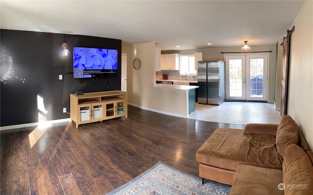 living room with wood-type flooring, a barn door, sink, and french doors