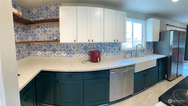 kitchen featuring sink, white cabinetry, stainless steel appliances, a barn door, and decorative backsplash