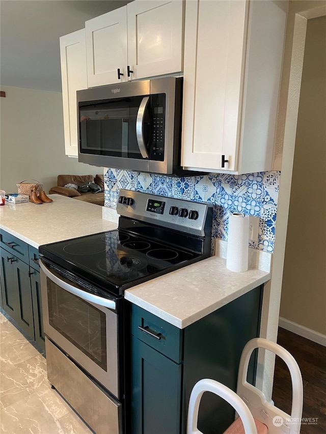 kitchen featuring appliances with stainless steel finishes, blue cabinetry, white cabinets, and decorative backsplash