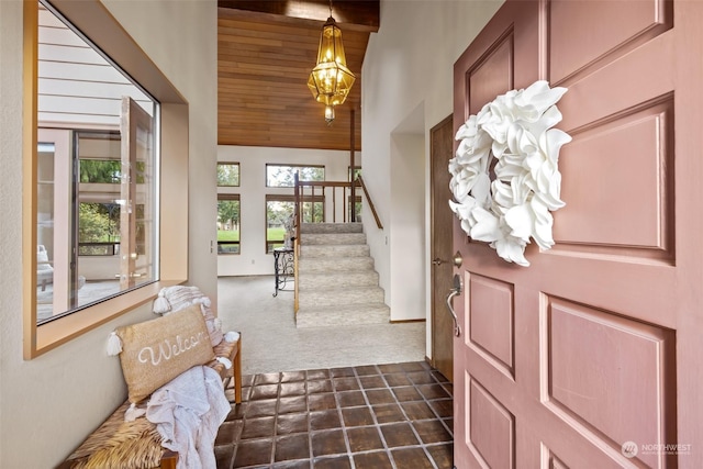 foyer with a notable chandelier, dark carpet, and wooden ceiling