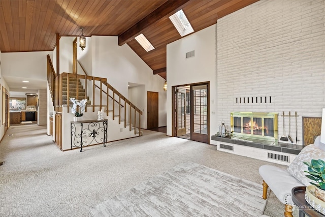 unfurnished living room featuring carpet floors, a skylight, a tiled fireplace, high vaulted ceiling, and wooden ceiling