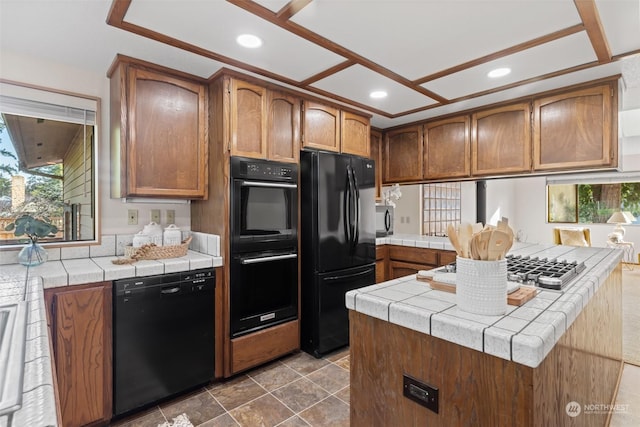 kitchen with black appliances, kitchen peninsula, and tile countertops