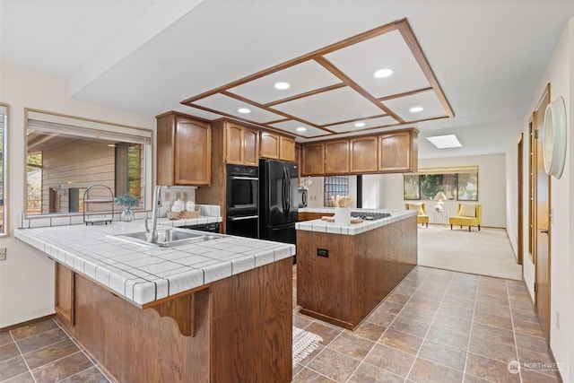 kitchen featuring tile counters, black appliances, plenty of natural light, and a kitchen island