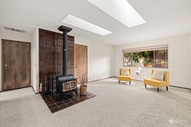 living room featuring a wood stove, dark carpet, and a skylight