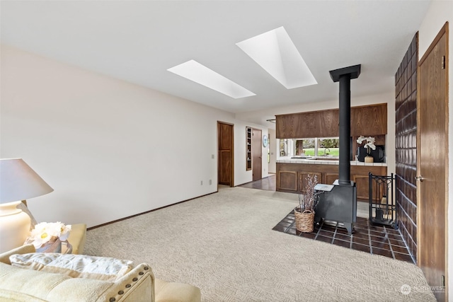 carpeted living room featuring a skylight and a wood stove