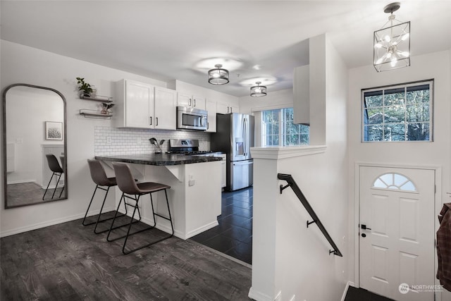 kitchen featuring appliances with stainless steel finishes, pendant lighting, a breakfast bar area, white cabinets, and kitchen peninsula