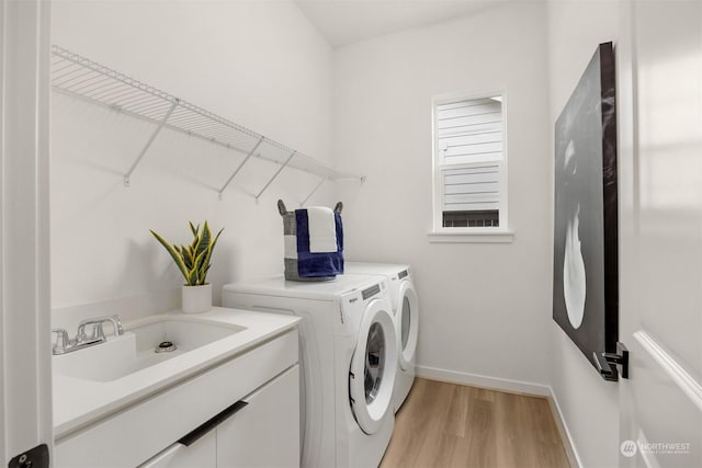 washroom with separate washer and dryer, sink, and light wood-type flooring