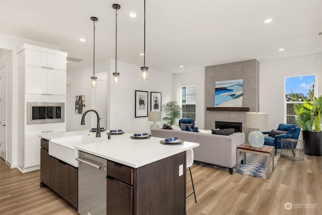 kitchen with sink, dark brown cabinetry, a kitchen island with sink, and a fireplace