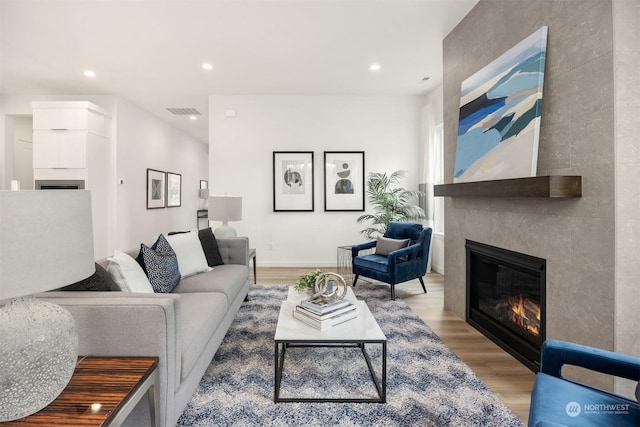 living room featuring light hardwood / wood-style flooring and a tiled fireplace