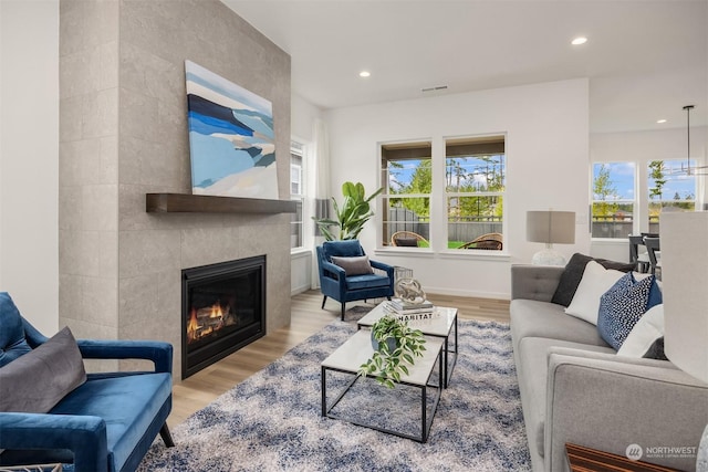 living room featuring a tile fireplace and light hardwood / wood-style floors