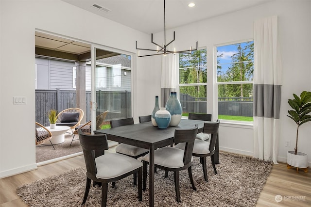 dining area with light wood-type flooring and a notable chandelier