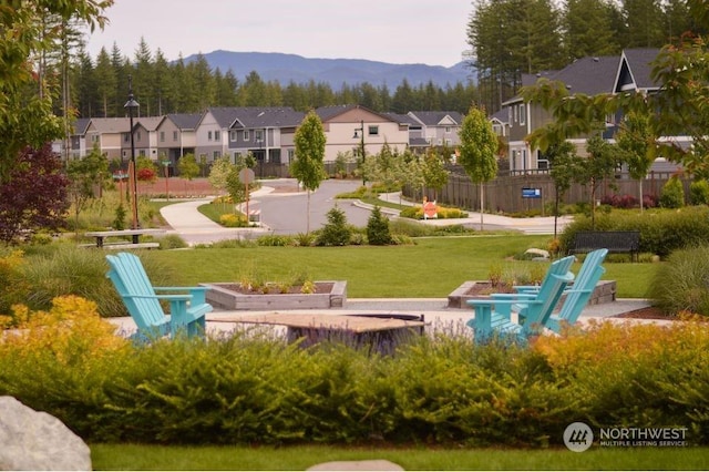 view of community featuring a mountain view, a yard, fence, and a residential view