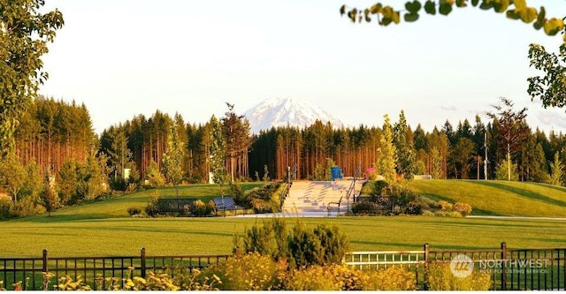 view of community with a mountain view, fence, and a lawn