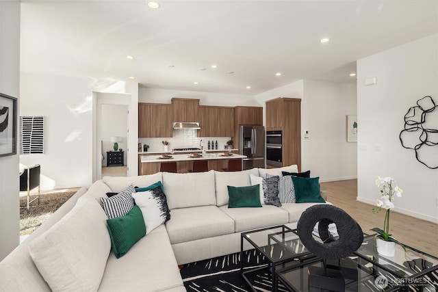 living room with baseboards, light wood finished floors, and recessed lighting