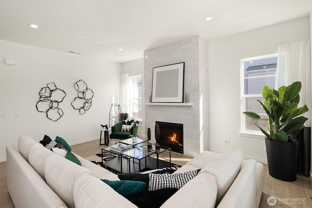 living room featuring light wood finished floors, a fireplace, baseboards, and recessed lighting