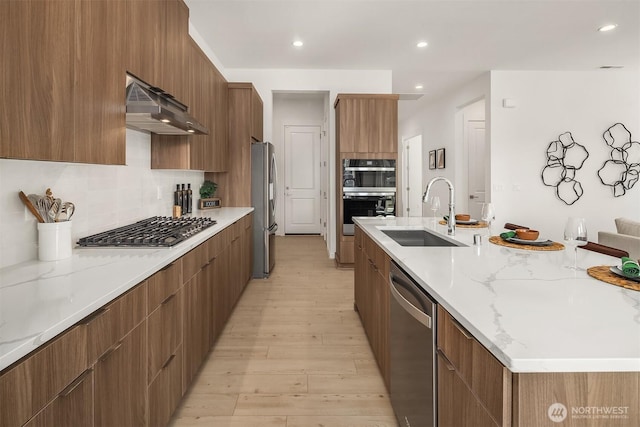 kitchen featuring under cabinet range hood, stainless steel appliances, a sink, tasteful backsplash, and modern cabinets