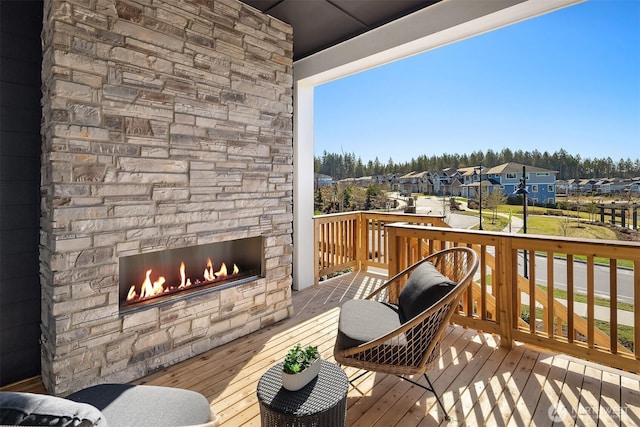 view of wooden balcony featuring a residential view, an outdoor stone fireplace, and a deck