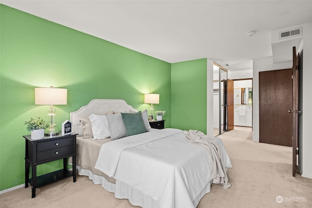 bedroom with light colored carpet and connected bathroom