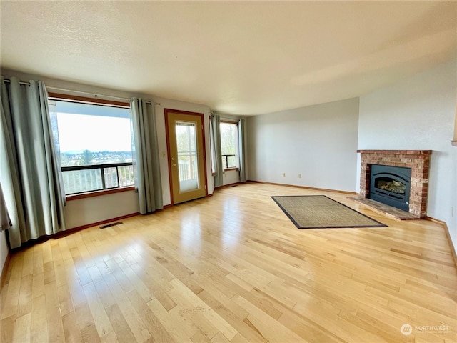 unfurnished living room with a textured ceiling, light hardwood / wood-style floors, and a fireplace